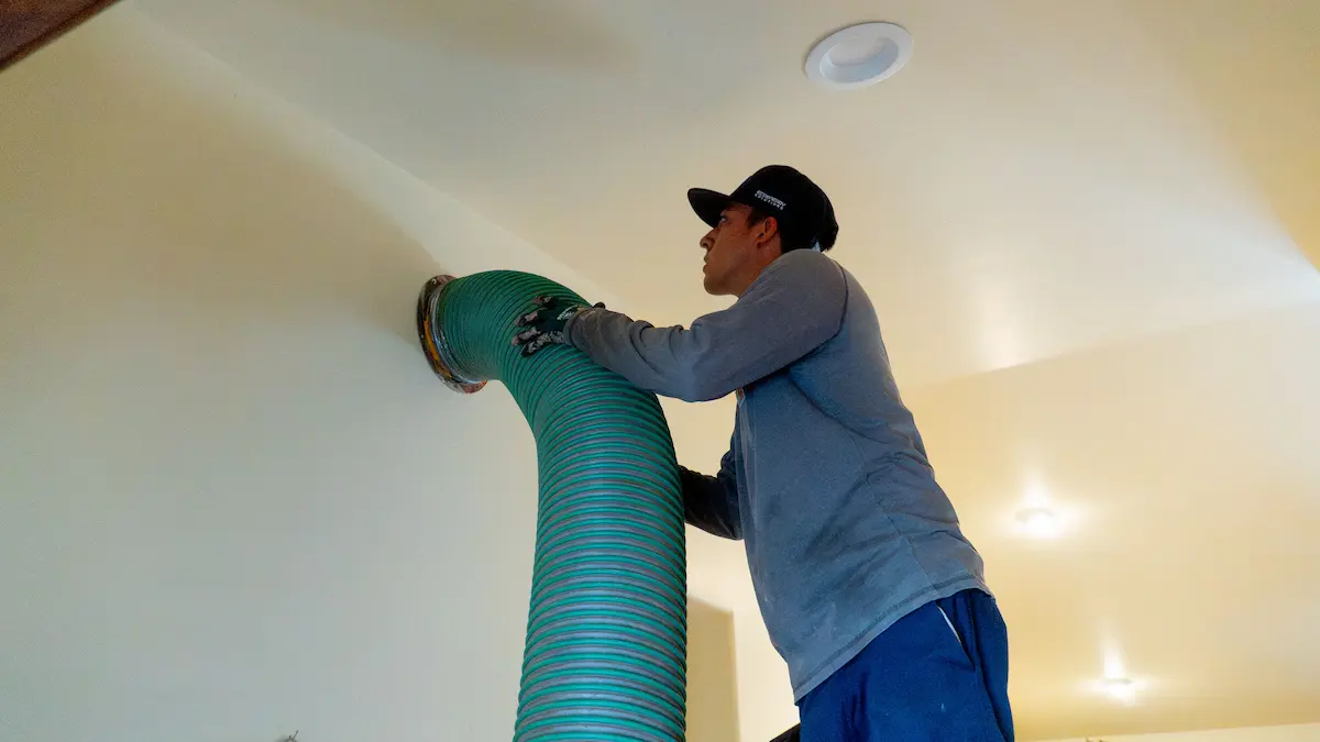 EcoEnergy Solutions technician connecting and sealing a flexible air duct to a ceiling boot in a Yuma, AZ home
