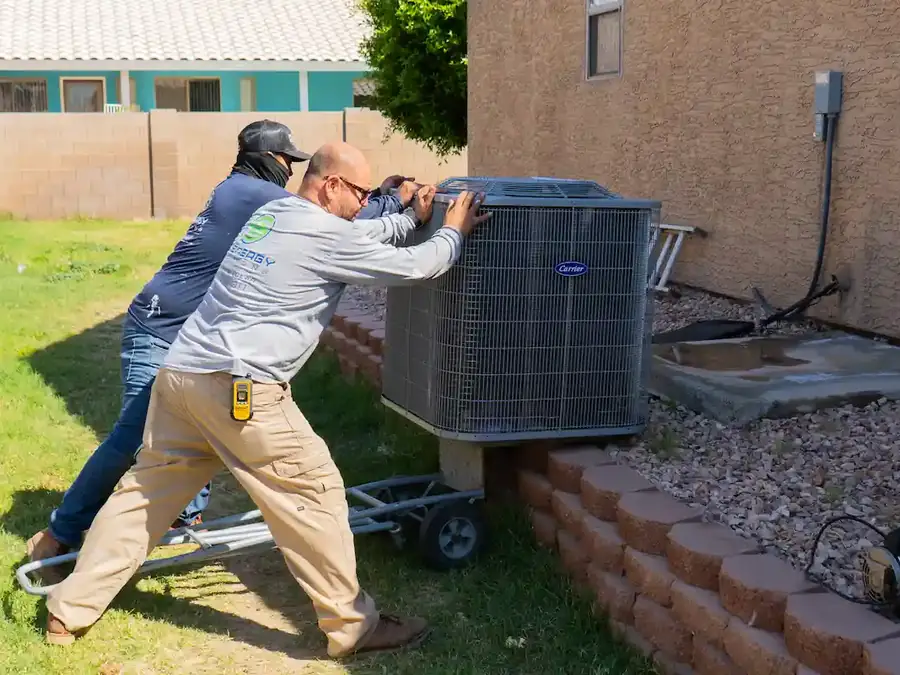 EcoEnergy Solutions technicians setting a new Carrier condenser on its pad at a Yuma, AZ home