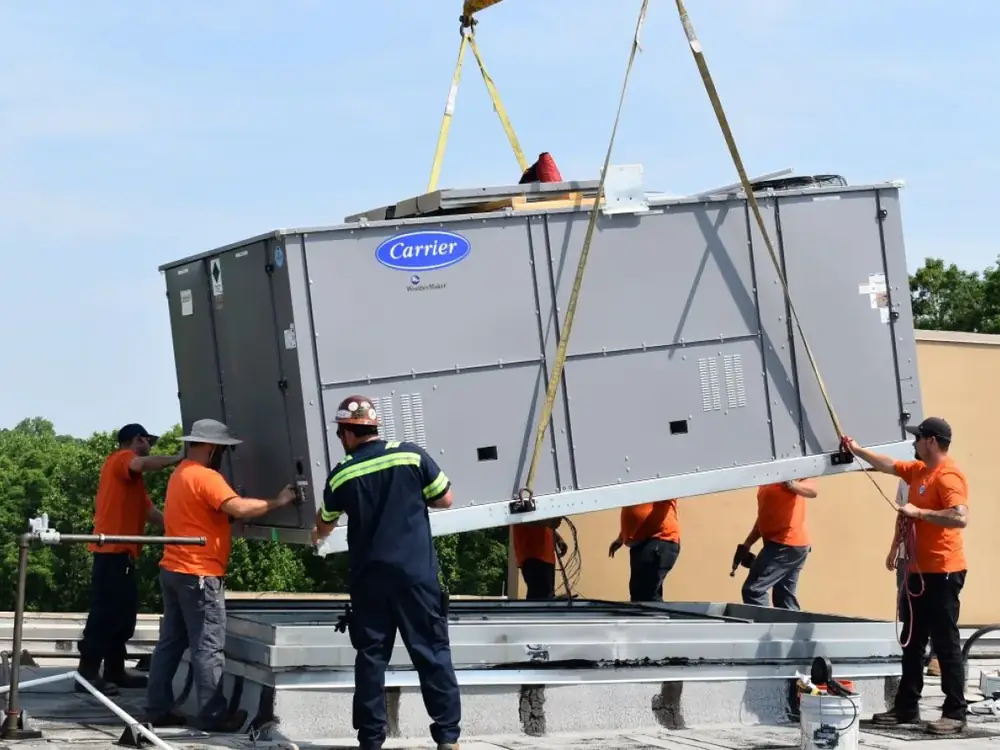 Commercial Carrier WeatherMaker rooftop unit installation in Yuma, AZ by EcoEnergy Solutions EcoEnergy Solutions crew lowering a Carrier WeatherMaker packaged rooftop unit onto a commercial roof in Yuma, AZ