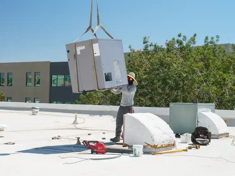EcoEnergy Solutions technician steadying a packaged rooftop unit as the crane lowers it in Yuma, AZ