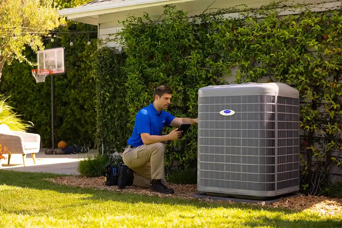 EcoEnergy Solutions technician documenting a heating system assessment on a tablet beside an outdoor heat pump at a Yuma, AZ home