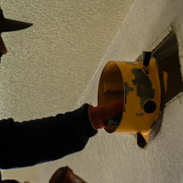 Technician installing a component into a wall vent