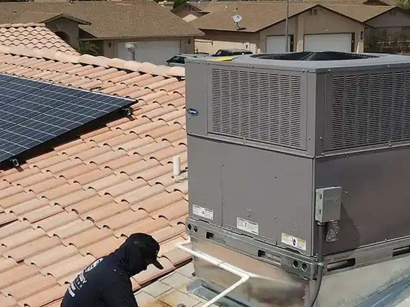 EcoEnergy technician working beside a rooftop package air conditioning unit on a tile roof in Yuma, AZ