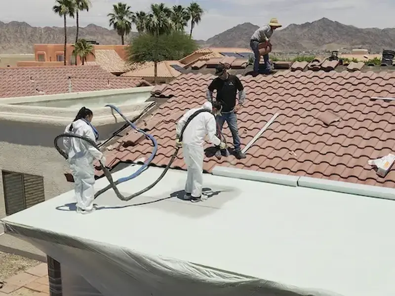 Crew in protective suits applying spray foam insulation on a flat roof section
