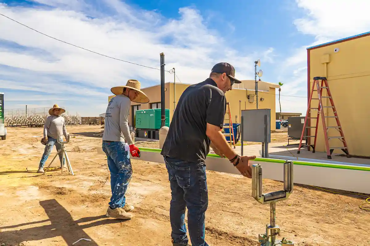 EcoEnergy Solutions crew running a seamless gutter through the roll-forming machine on a jobsite in Yuma, AZ