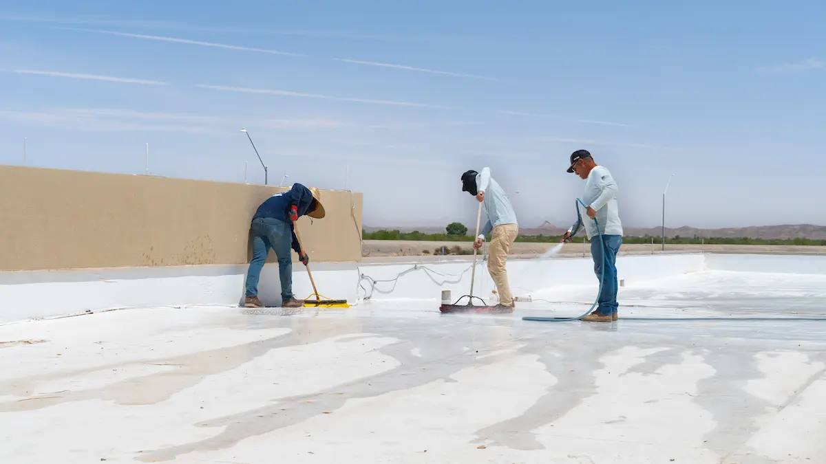 EcoEnergy Solutions crew spreading and rinsing a reflective coating during a flat roof repair in Yuma, AZ