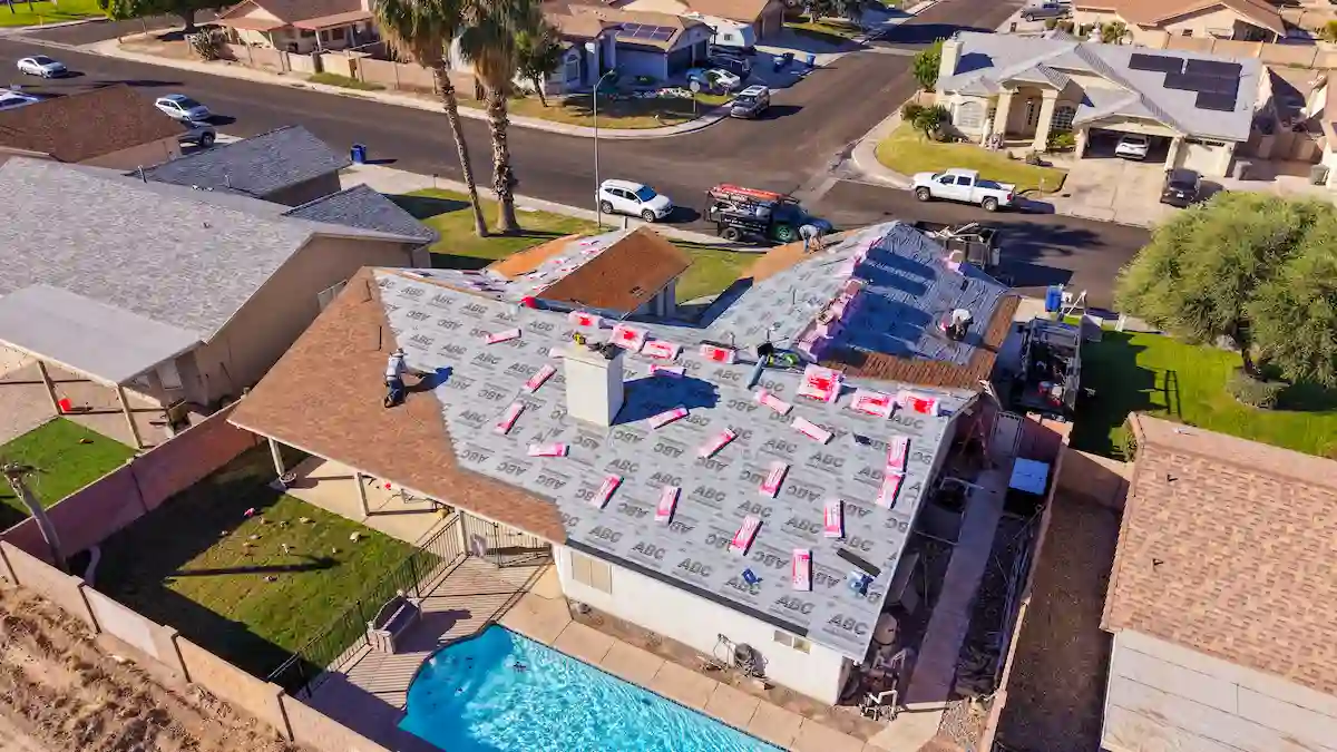 EcoEnergy Solutions crew with synthetic underlayment laid and shingle bundles staged across the roof during a full replacement in Yuma, AZ