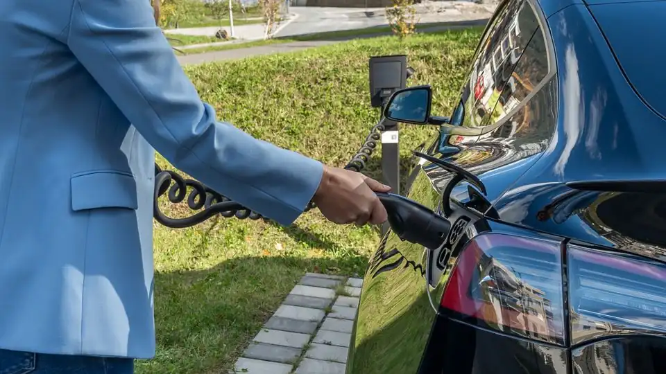 Driver Connecting an Electric Vehicle to an Outdoor Charging Station